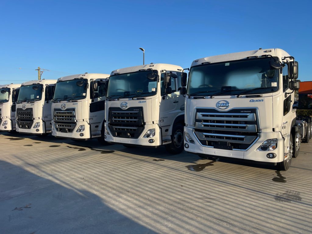 Rows of new white semi-trucks at an Australian truck dealership lot representing national heavy vehicle dealer registration services.