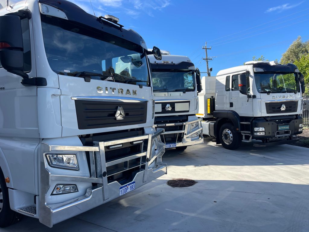 Fleet manager efficiently managing multiple truck registrations with heavy vehicles ready for delivery in Australia.